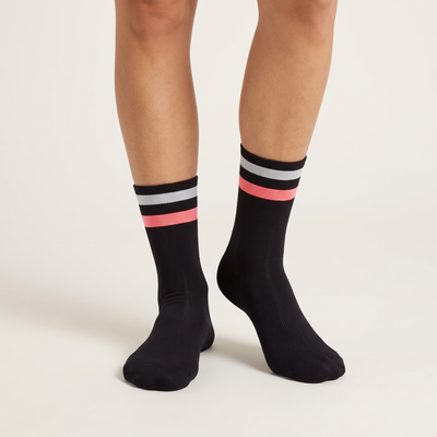 Two Stripe mid-length cycling socks on feet, front view, black with a pale gray and a pink stripe at the cuff